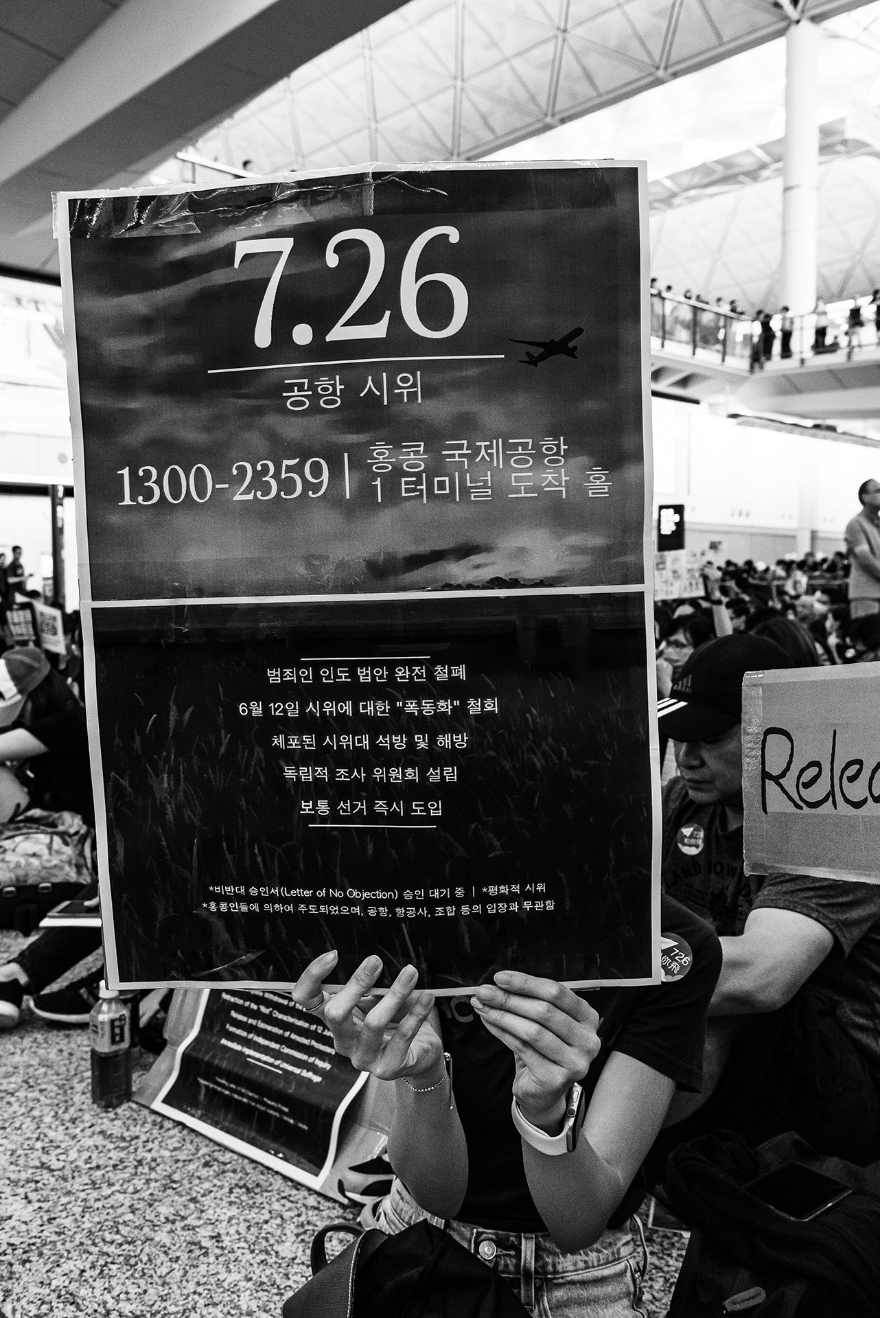 홍콩 공항 시위 일정과 다섯 가지 요구가 적힌 피켓을 든 참가자